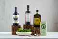 Premium Spanish olive oil tasting box with four bottles displayed on wooden stands with fresh salad